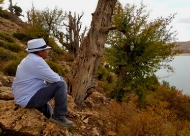 Pierre Gino assis au bord d'un lac, entre les arbres